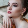Stunning close-up portrait of a woman with elegant makeup and jewelry, epitomizing modern fashion and beauty.